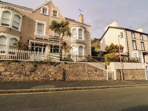 A two-story building with a stone facade, large windows, and a balcony with a white railing. - Tudno Lodge (Llandudno)