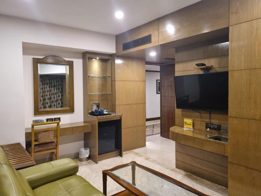 A modern living room with a sofa, a coffee table, a TV, and a small kitchenette area.