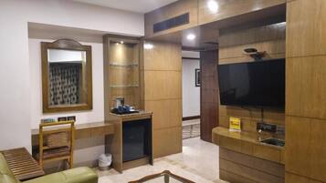 Una sala de estar moderna con un sofá, una mesa de centro, un televisor y una pequeña zona de kitchenette.