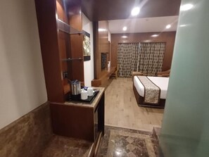 Una habitación de hotel con cama, una mesita con hervidor y zona de ducha.