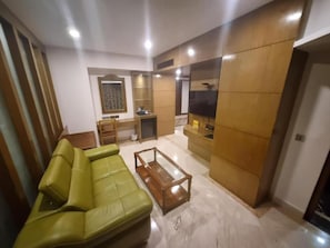 A living room with a green sofa, a wooden coffee table, and a TV. - Benzz Park -Chennai (Chennai)