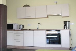 A kitchen with white cabinets, a microwave, a coffee maker, and an oven. - Holiday apartment with 2 bedrooms (Parchtitz)