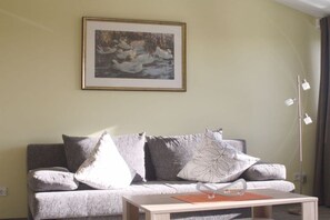 A living room with a grey sofa, a framed picture on the wall, and a floor lamp. - Holiday apartment with 2 bedrooms (Parchtitz)