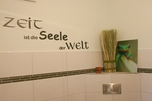 A bathroom with a wall-mounted sign that reads 'Zeit ist die Seele der Welt' and a framed picture of a frog. - Holiday apartment with 2 bedrooms (Parchtitz)