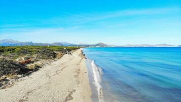 A beach with clear blue water, a sandy shore, and distant mountains.