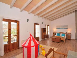A room with a bed, a wooden chair, a small table, a lamp, and a circus tent. - Holiday Home in Muro With Swimming Pool (Muro)