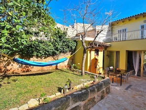 A yellow building with a balcony, a hammock, and a patio area with a table and chairs. - Holiday Home in Muro With Swimming Pool (Muro)