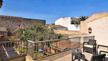 A patio area with outdoor furniture, a stone wall, and a view of a building with a tiled roof.