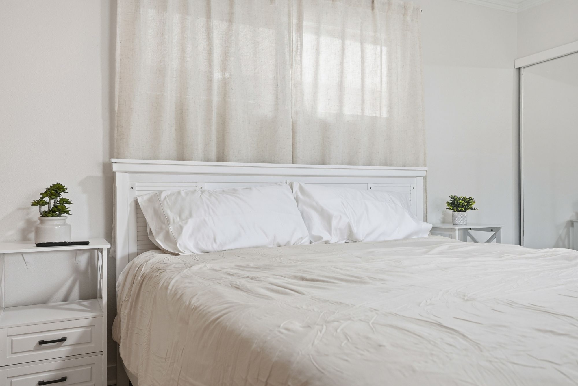 A white bedroom with a bed, two bedside tables, and a nightstand.