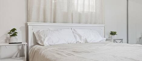 A white bedroom with a bed, two bedside tables, and a nightstand.