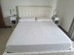 Una habitación de hotel estándar con una cama, dos mesitas de noche y una mesilla.