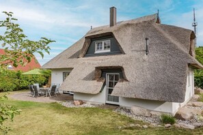 A thatched-roof house with a chimney, a window, and a door. - Holiday home with 3 bedrooms (Heringsdorf)