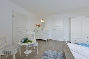 A bedroom with a bed, a dresser, a vanity with a mirror, a small round table with a candle, and a chair. - Holiday apartment with 2 bedrooms (Breege)