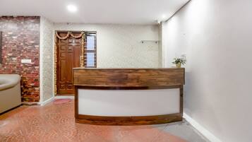 Un mostrador de recepción con detalles de madera, una pared con diseño, una pared de ladrillo y un suelo de baldosas.