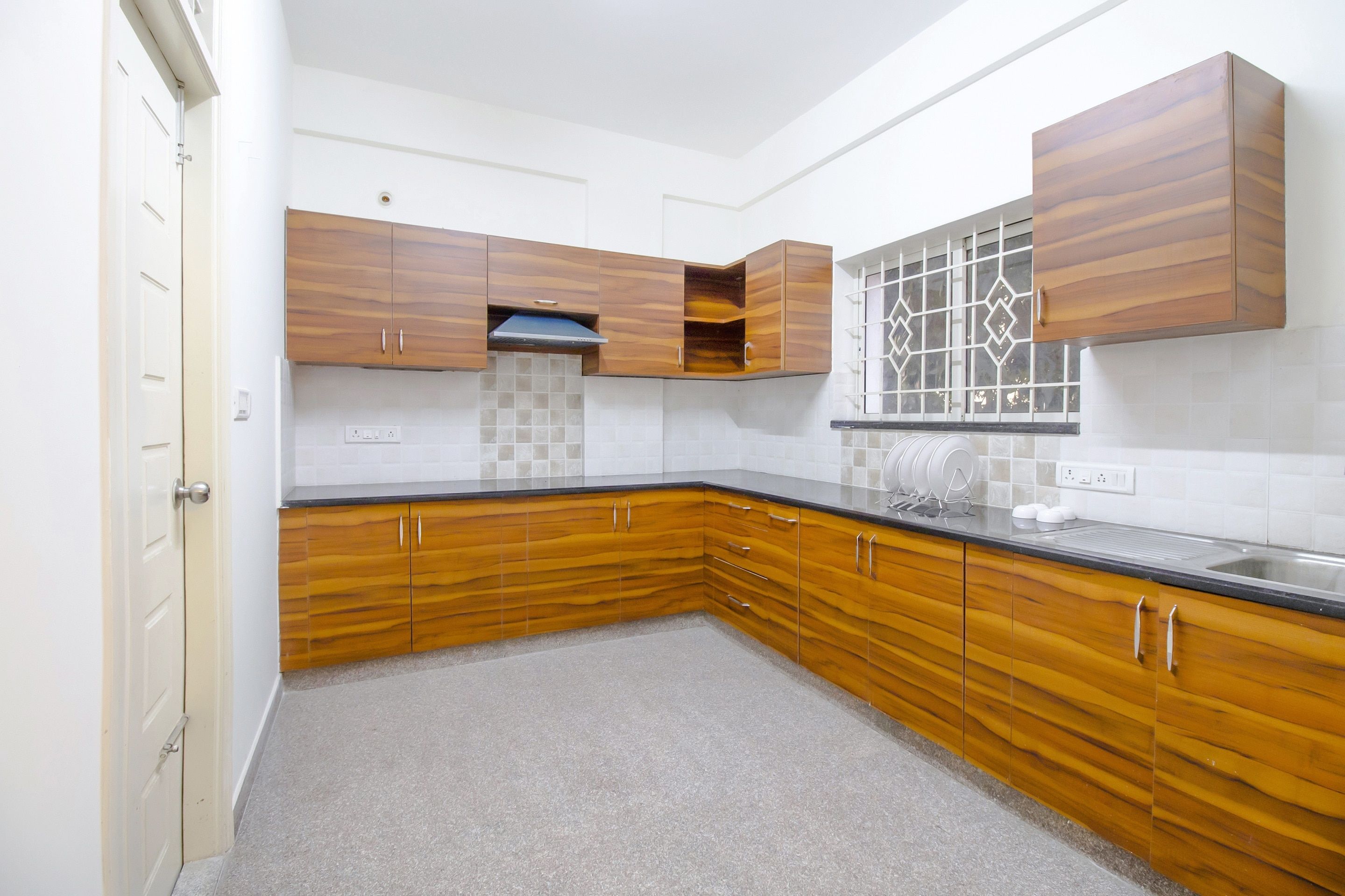 A kitchen with wooden cabinets, a tiled backsplash, and a window with decorative glass.