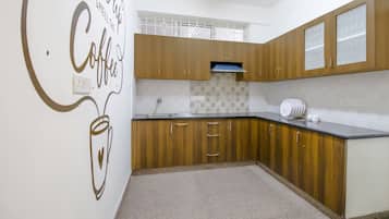 A kitchen with wooden cabinets, a countertop, and a wall with a coffee-themed design.