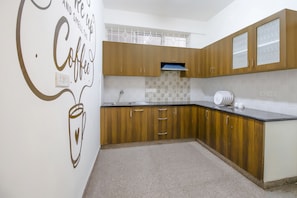 Cuina amb armaris de fusta, una taulell i una paret amb un disseny temàtic de cafè.