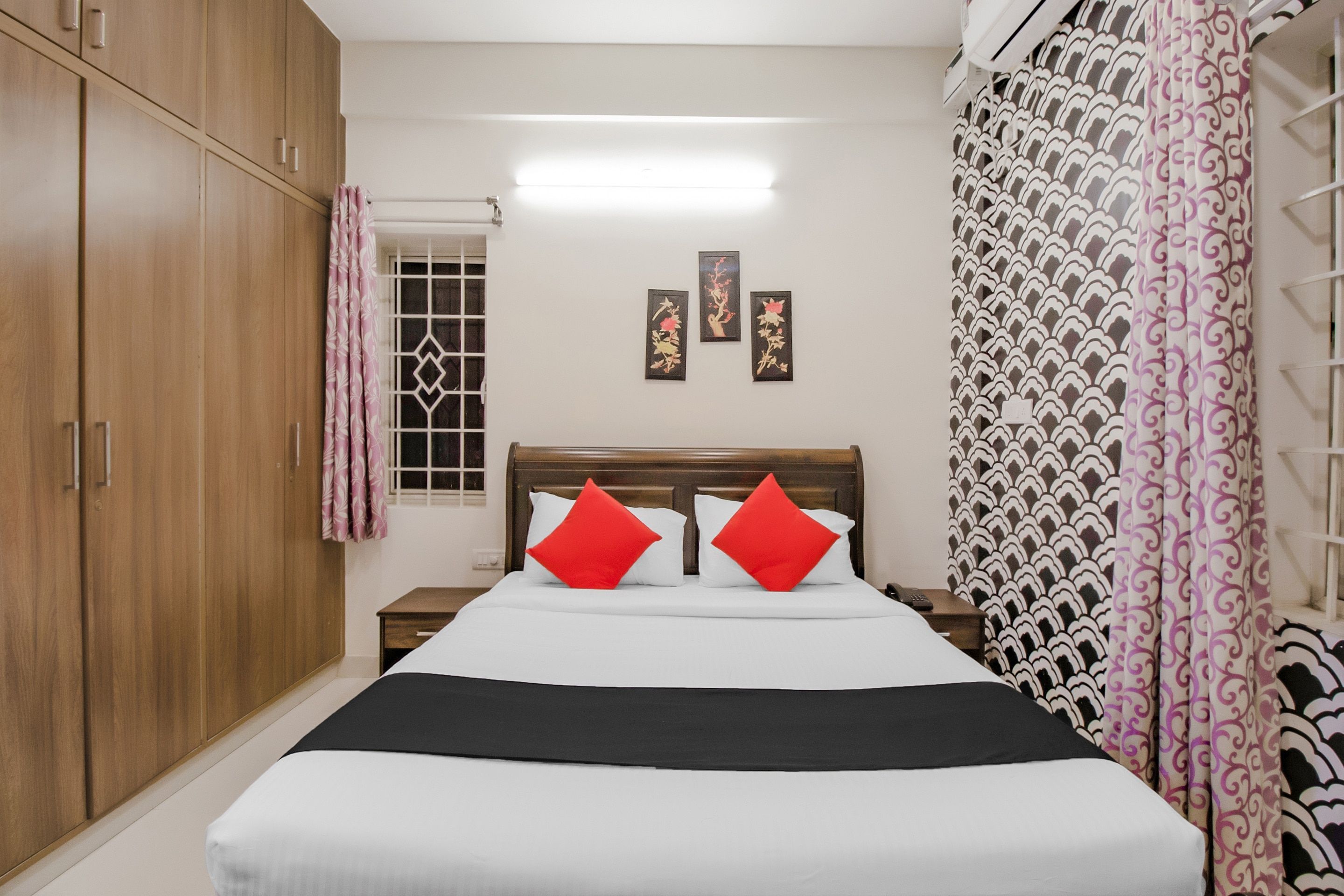 Un dormitorio con cama, armario, mesita de noche y ventana con cortinas.