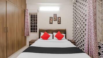 Un dormitorio con cama, armario, mesita de noche y ventana con cortinas.