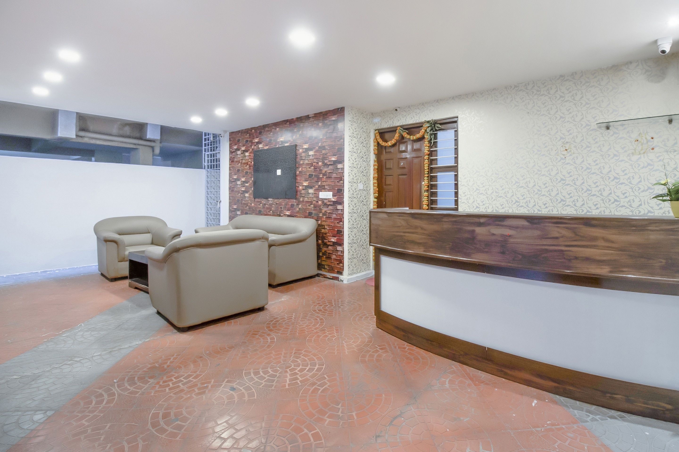 A reception area with a wooden reception desk, two beige armchairs, and a patterned wall.