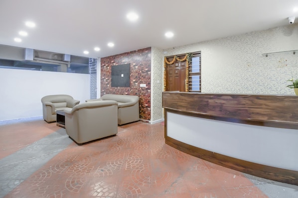 A reception area with a wooden reception desk, two beige armchairs, and a patterned wall.
