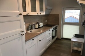 Una cucina con mobili bianchi, un lavello, un tostapane e una finestra.