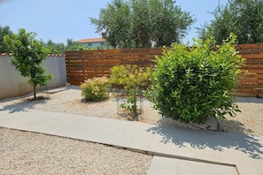 A garden with a gravel path, wooden fence, and various shrubs. - Holiday home in Pula with barbecue and Wi-Fi (Pula)
