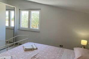A bedroom with a bed, a window, a bedside lamp, and a chair. - Holiday home in Pula with barbecue and Wi-Fi (Pula)