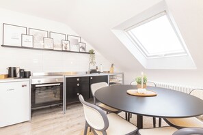 A modern kitchen with a dining area, featuring a Bosch refrigerator, a built-in oven, a black dining table with four chairs, and a skylight above. - Vrbo Property (Meerbusch)