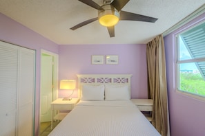 A bedroom with a bed, a nightstand, a ceiling fan, and a window with curtains. - 2BR Key West condo with pool, hot tub, kitchen, WiFi (Key West)