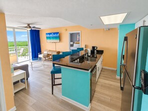 A modern kitchen with a central island, a dining area with a table and chairs, and a view of a balcony. - 2BR Key West condo with pool, hot tub, kitchen, WiFi (Key West)