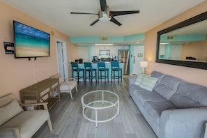 A living room with a grey sofa, a coffee table, and a TV mounted on the wall. - 2BR Key West condo with pool, hot tub, kitchen, WiFi (Key West)