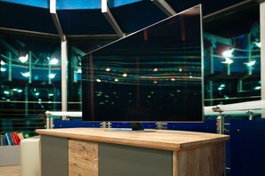 Un mostrador de recepción moderno con un monitor de pantalla plana, una encimera de madera y un separador de vidrio.