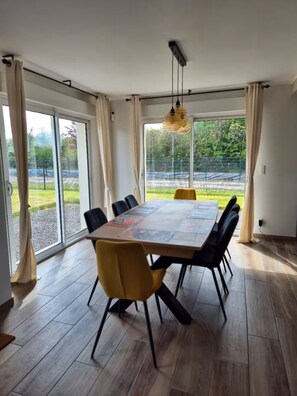 Un espace repas comprenant une grande table, des chaises et un luminaire suspendu.