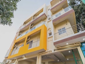 A multi-story building with balconies, air conditioning units, and visible structural elements.