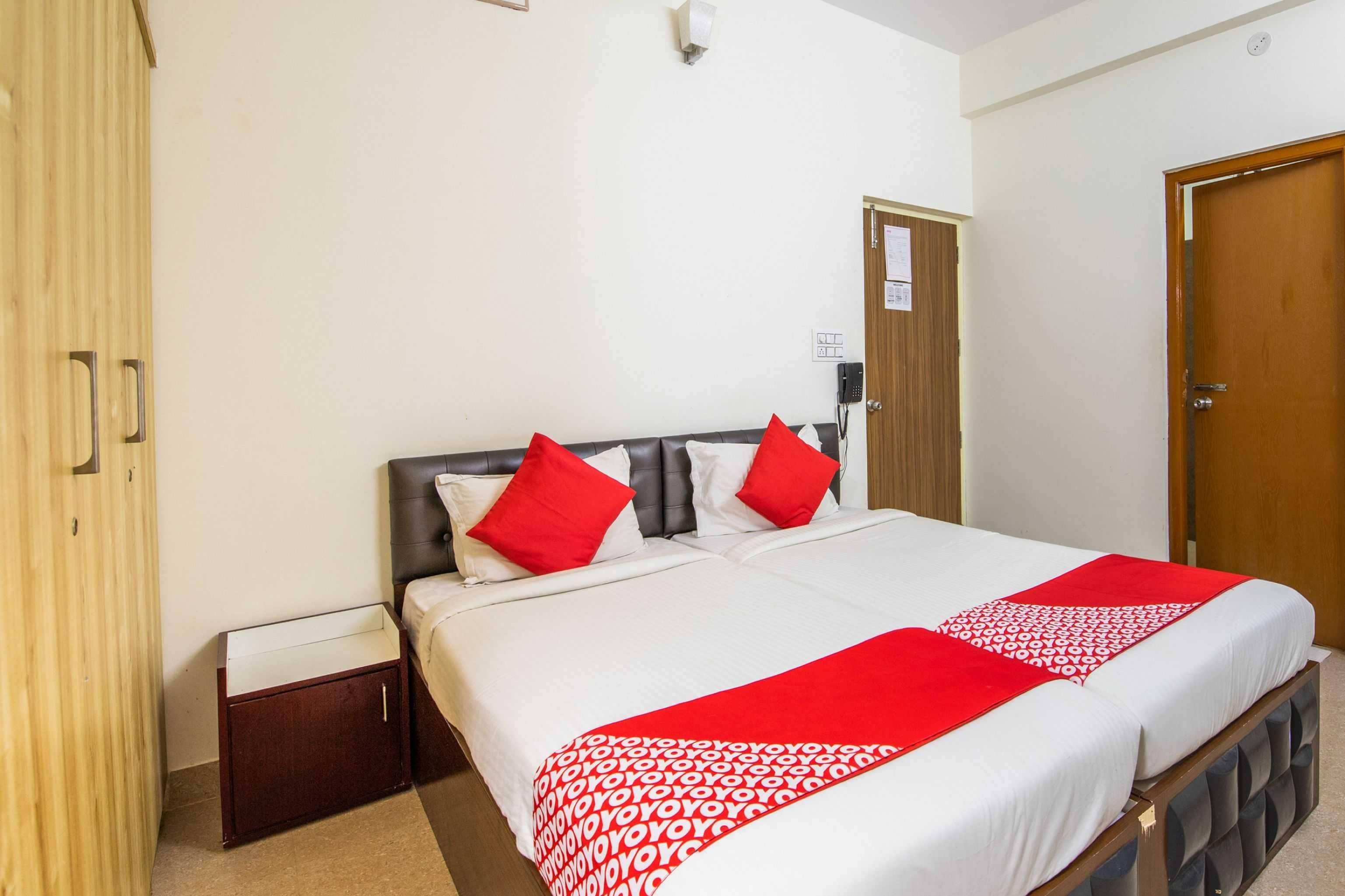 Una habitación de hotel con cama, armario de madera, mesita de noche y puerta.