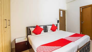 Una habitación de hotel con cama, armario de madera, mesita de noche y puerta.