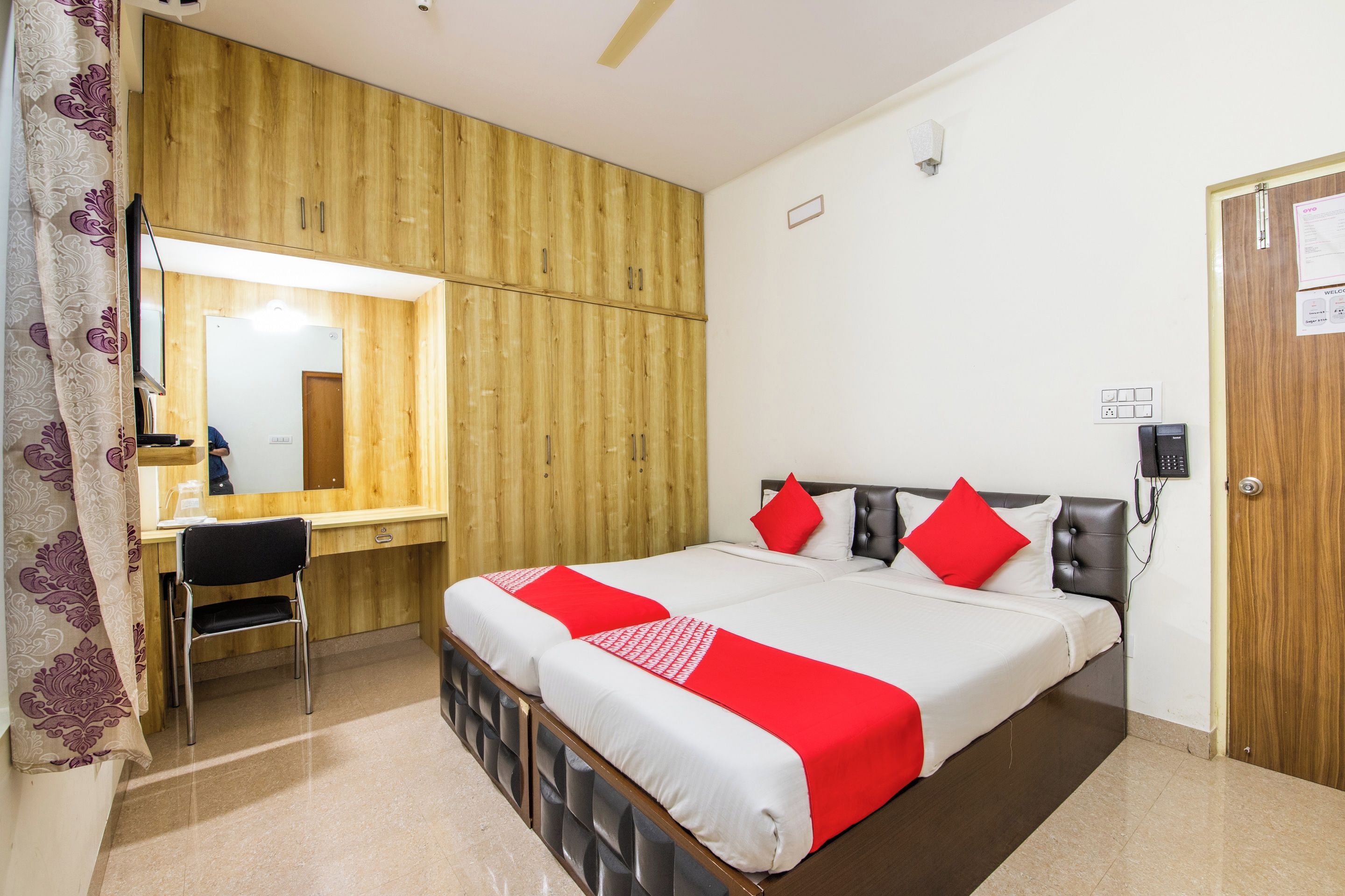 Ein Hotelzimmer mit Bett, Schreibtisch, Stuhl, Spiegel und Tür.