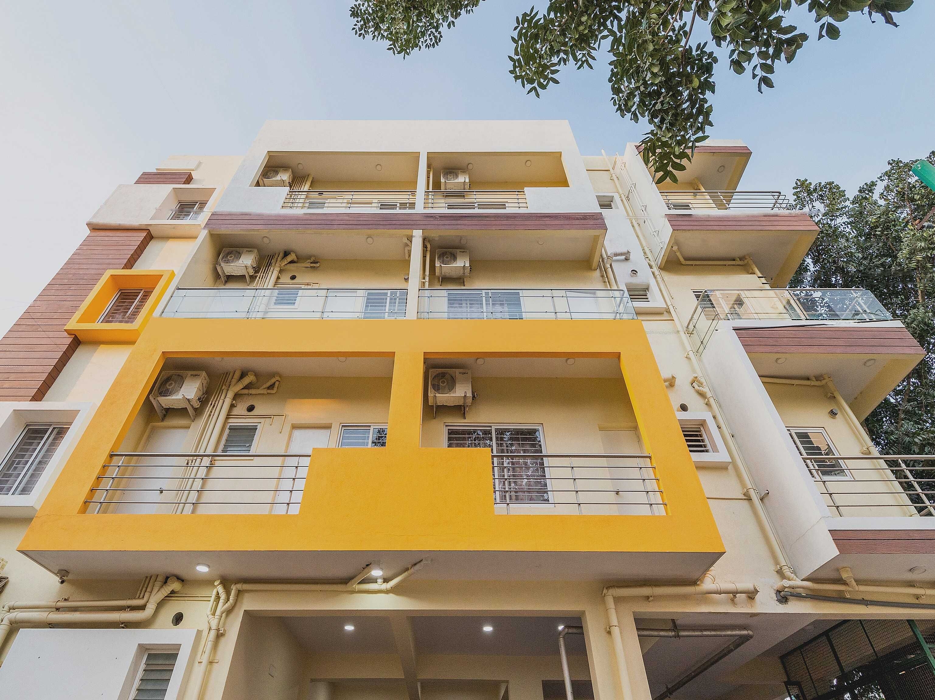 A multi-story building with balconies, air conditioning units, and a yellow accent wall.