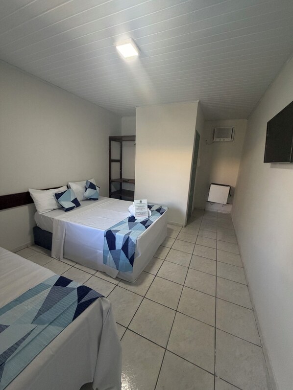 Una habitación de hotel con dos camas, un escritorio pequeño, una silla y un televisor.