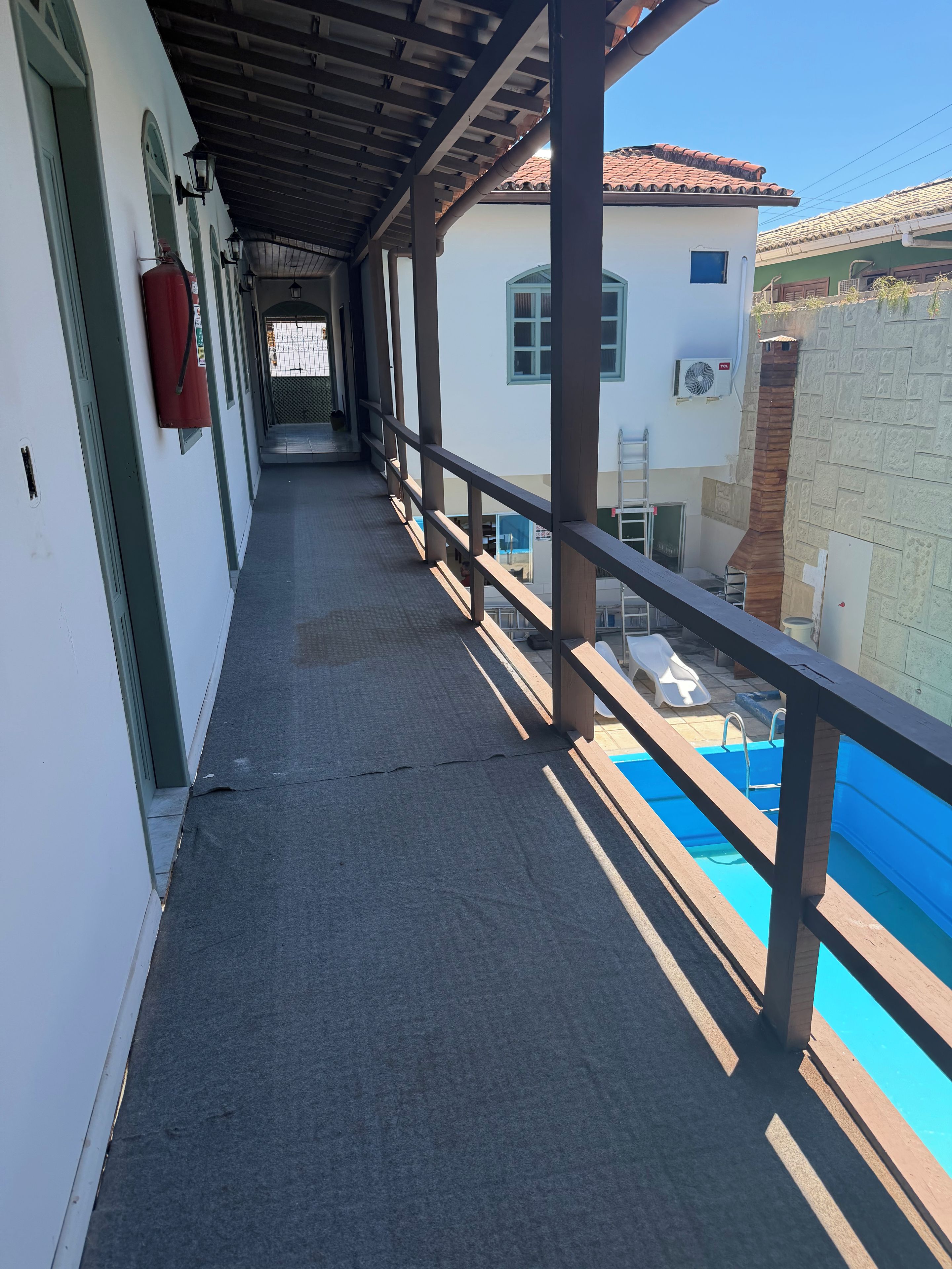 Un pasillo cubierto con una zona de piscina visible a través de la barandilla.