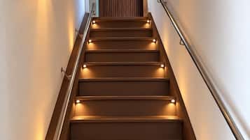 Un escalier doté d’une rampe et d’un éclairage fixé au mur.