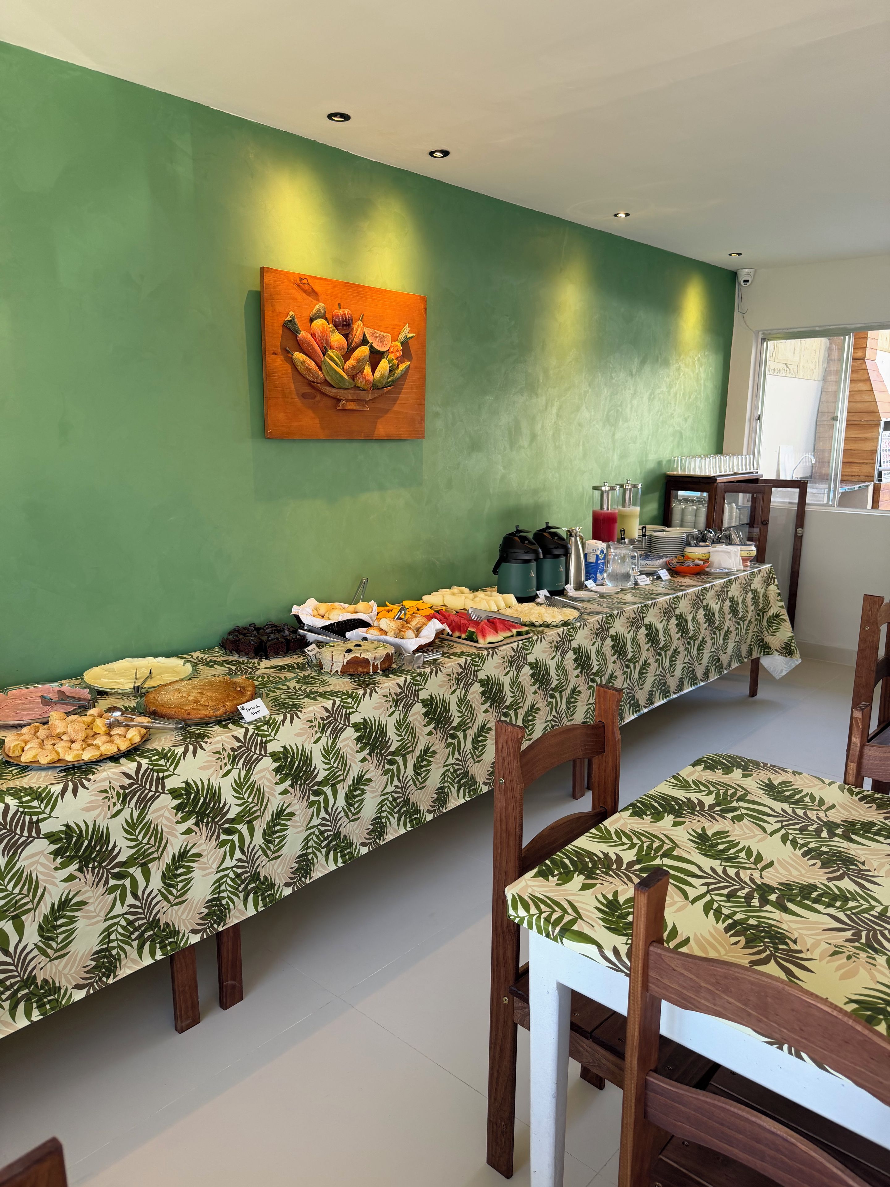 A buffet table with various food items, a wooden wall art, and a window with a view.