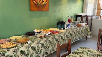 A buffet table with various food items, a wooden wall art, and a window with a view.