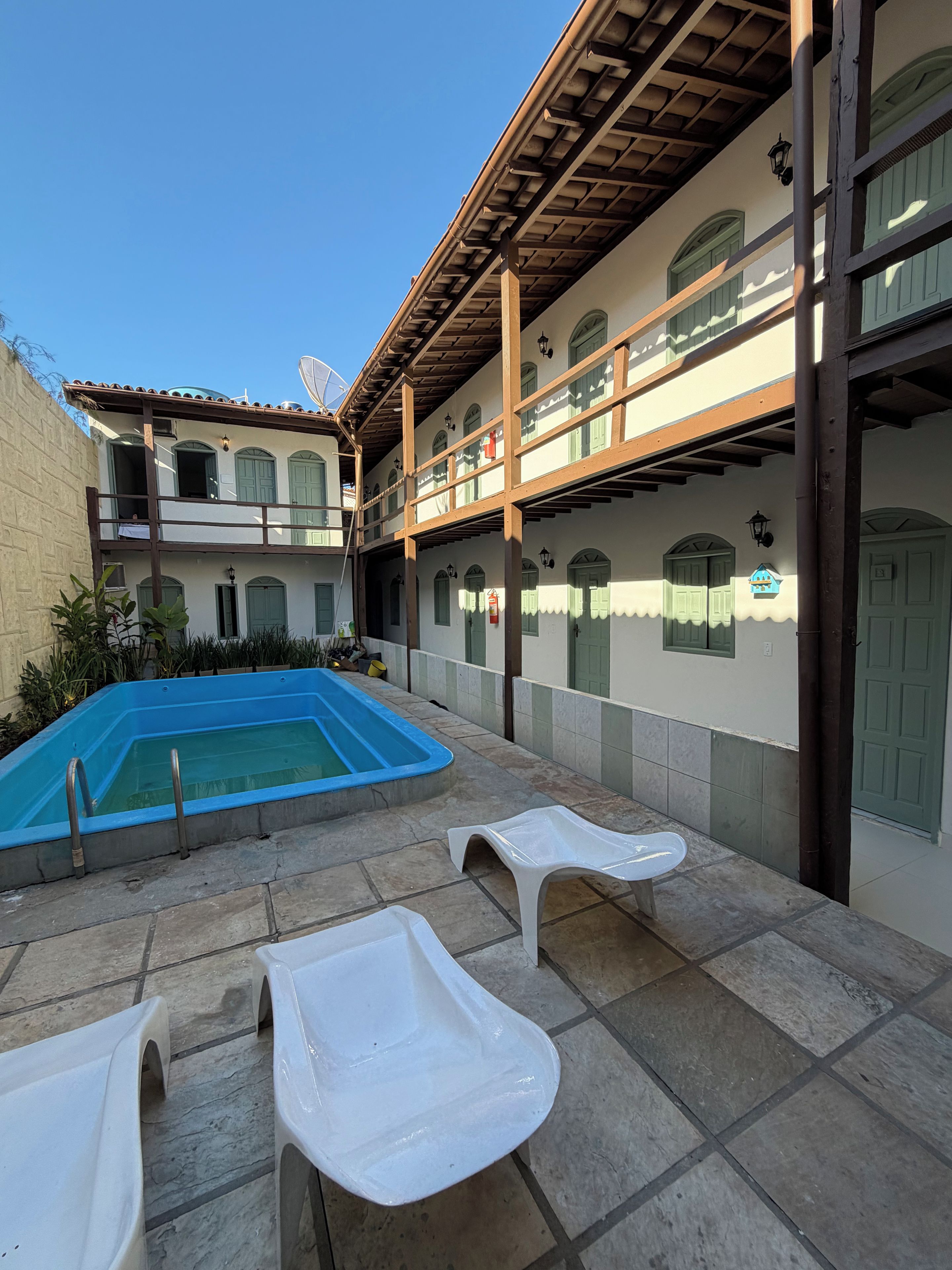 Un patio con piscina, mobiliario exterior y un edificio con varios balcones.