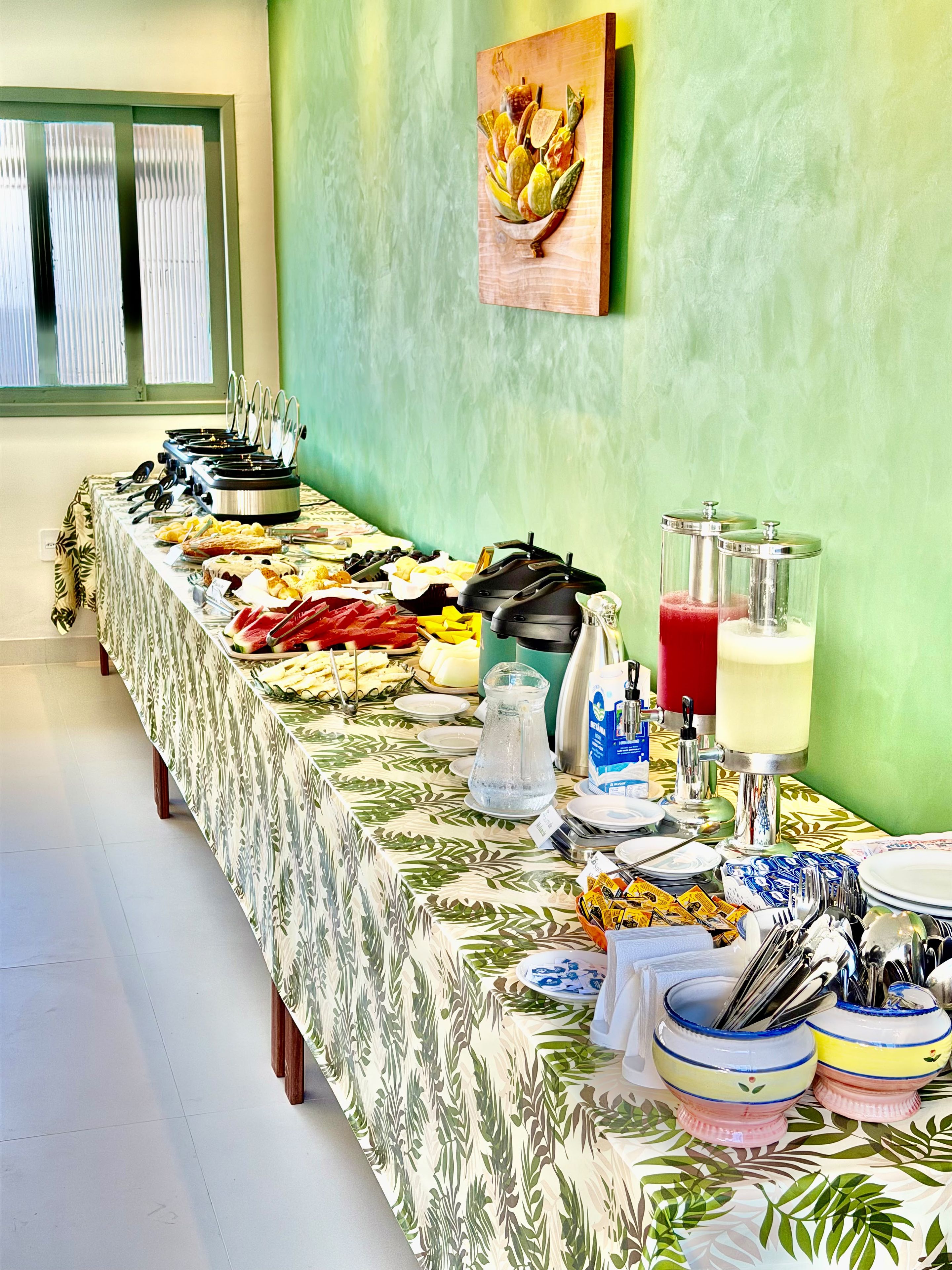 Un tavolo per il buffet con diversi cibi, una caraffa d'acqua e un distributore di succo.