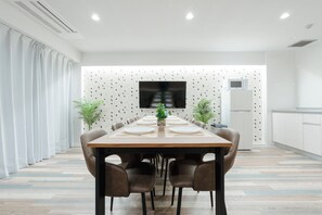 Un comedor moderno con una mesa larga, sillas y un televisor de pantalla plana montado en la pared.