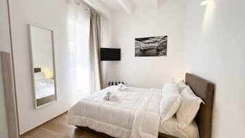 Ein Schlafzimmer mit einem Bett, einem Flachbildfernseher, einem großen Spiegel und einem gerahmten Bild an der Wand.