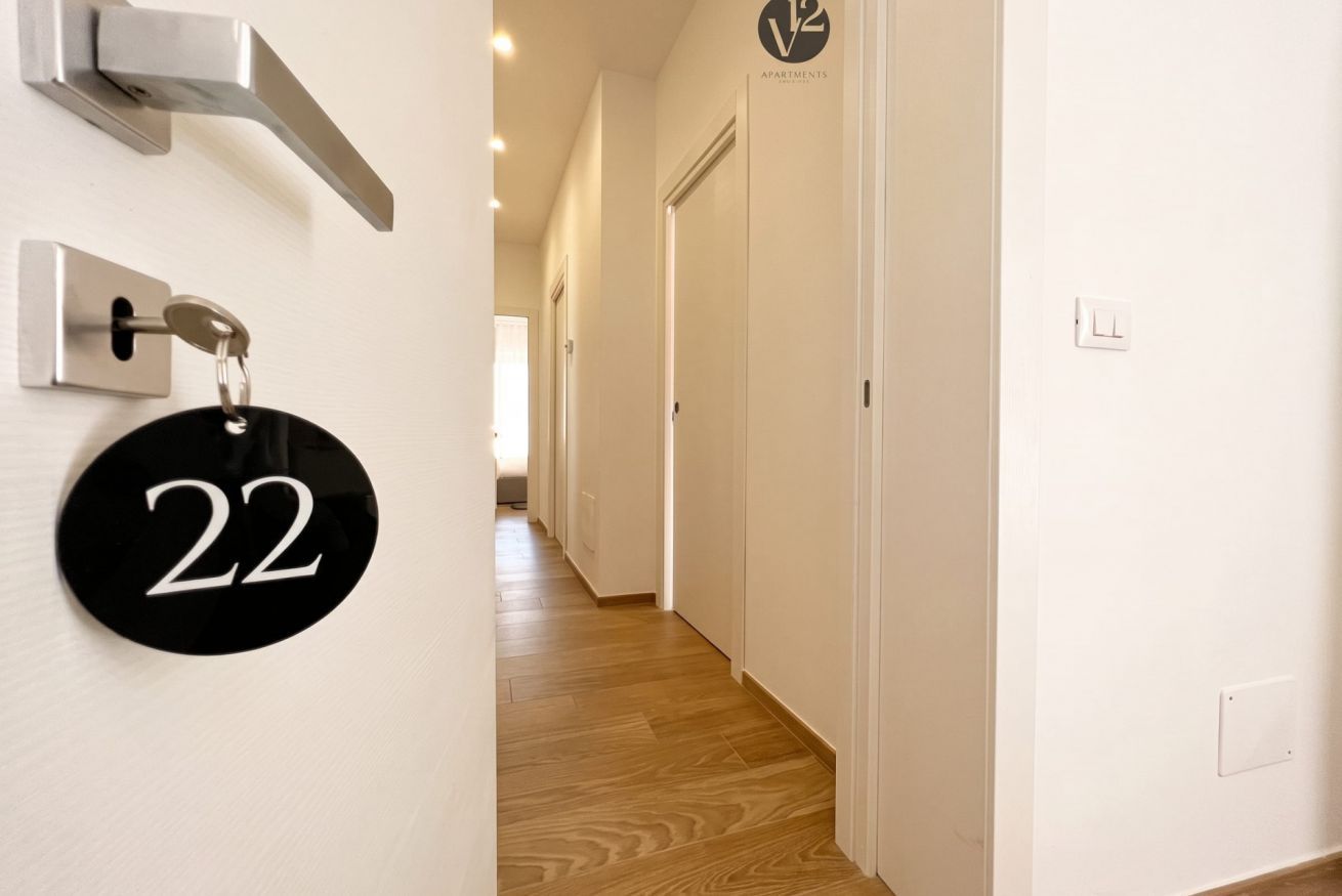 Un couloir avec une porte portant le numéro « 22 » et une pancarte indiquant « appartements ».