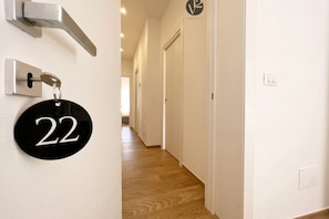 Un couloir avec une porte portant le numéro « 22 » et une pancarte indiquant « appartements ».